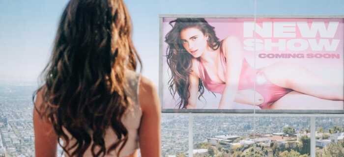 Sue stares at a billboard of herself outside her window